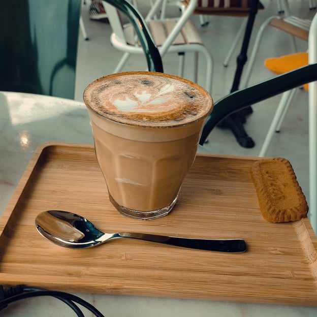 Cappuccino in a glass with a Lotus Biscuit.