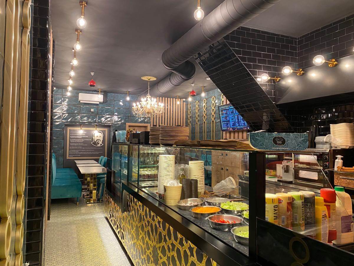 Qbap Pita Place, Ghent: Chic interior vibes and a bustling cooking station—where culinary wonders come to life in style.