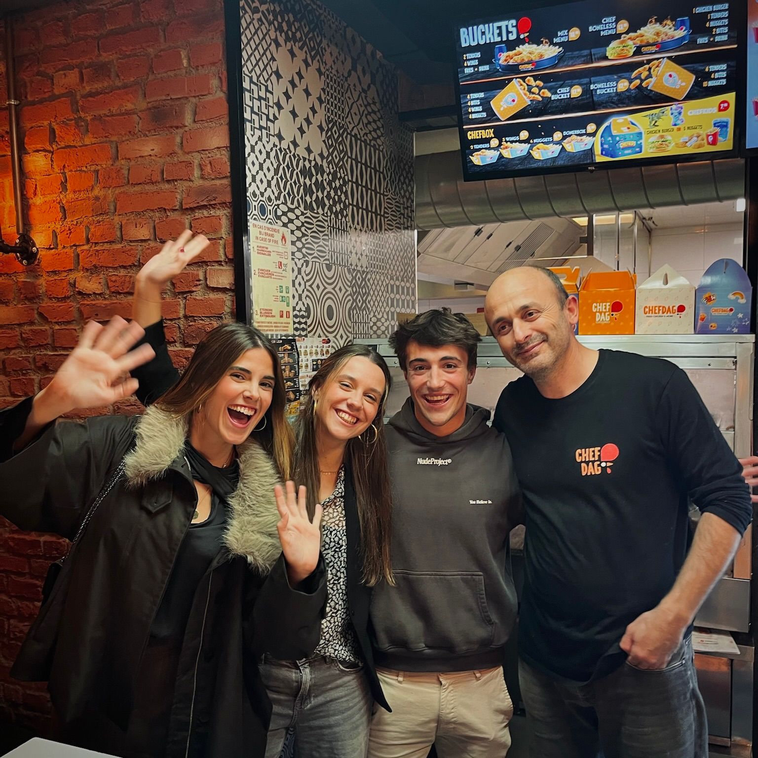 Group of students smiling and waving with staff at a late-night spot in Gent.