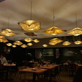 Dark dining room with white paper lamps, chairs & tables