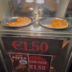 Display window of Pizza Overpoort showing two pizzas & an advertisement for €1.50 per slice