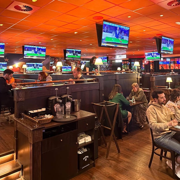 People eating and drinking while watching snooker on tv-screens