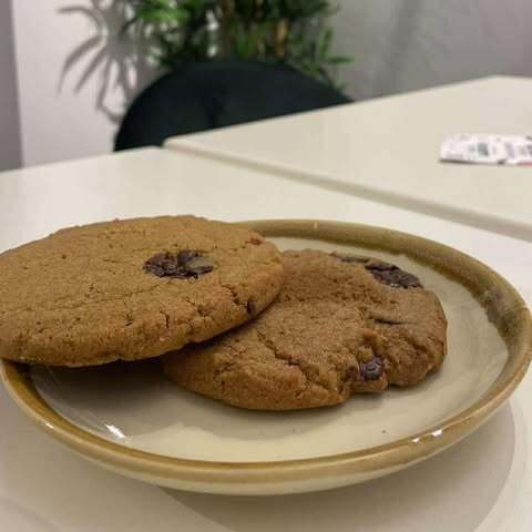 Two chocolate chip cookies on a plate, on a white table