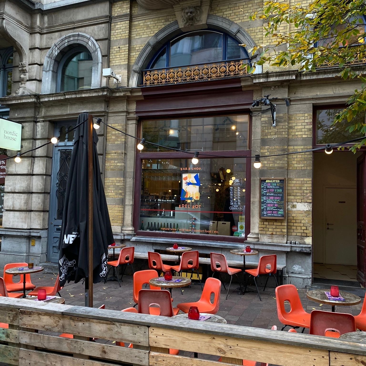 porch with some tables, red chairs and twinkle lights, in front of big window