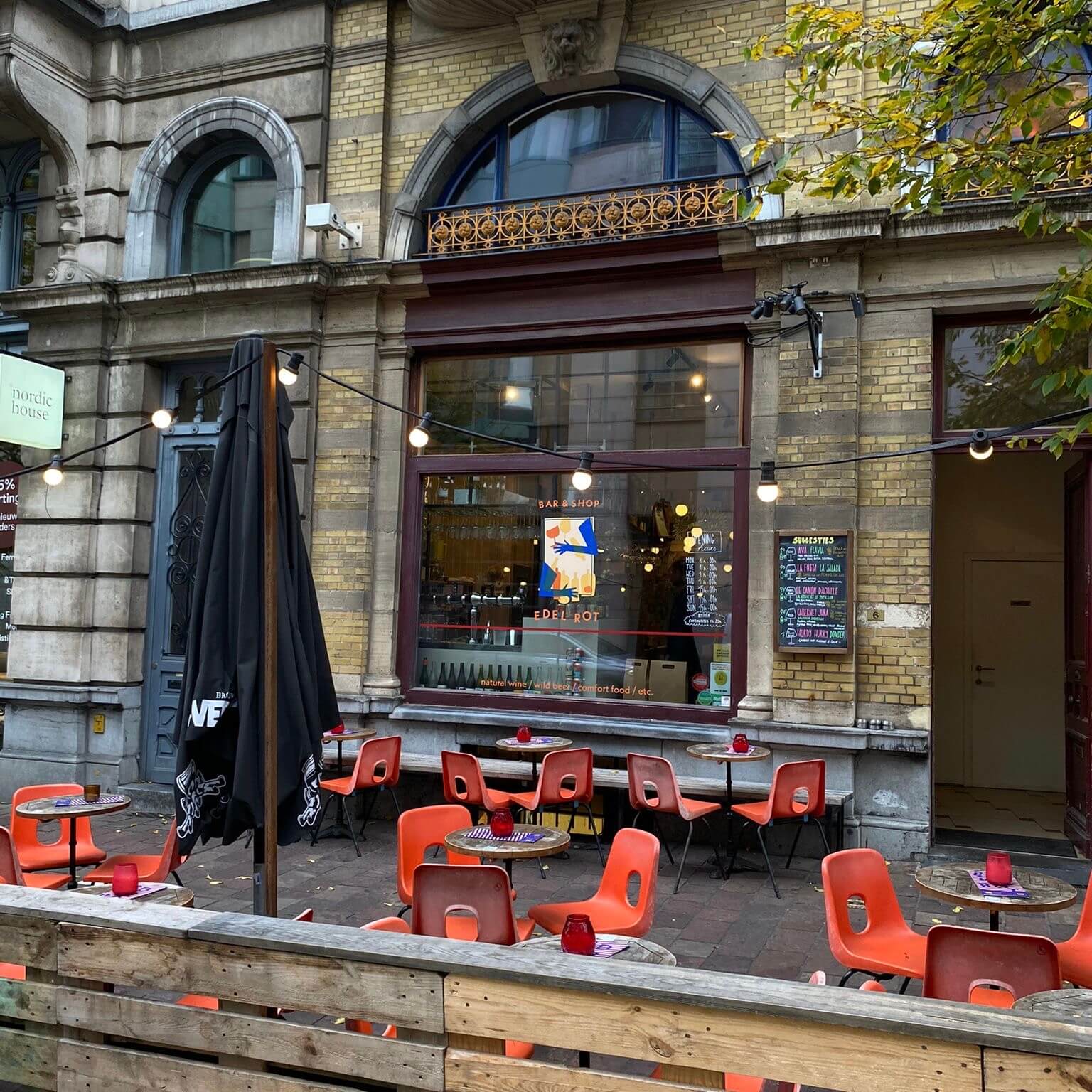 porch with some tables, red chairs and twinkle lights, in front of big window