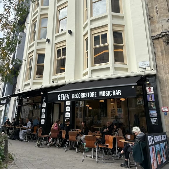 Outside of Gen X store. People sitting in front at coffee tables.