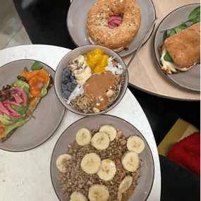 Plates with a bagel, a smoothie bowl with fruit and toast with salmon.