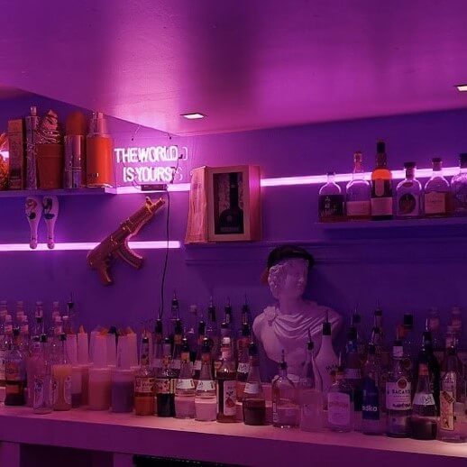 Pink neon cocktail bar with led sign and greek statue.