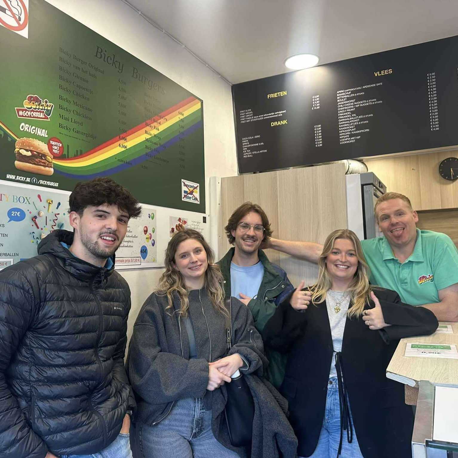 Five people standing in Stefano's Place, a snack bar, all looking happy.