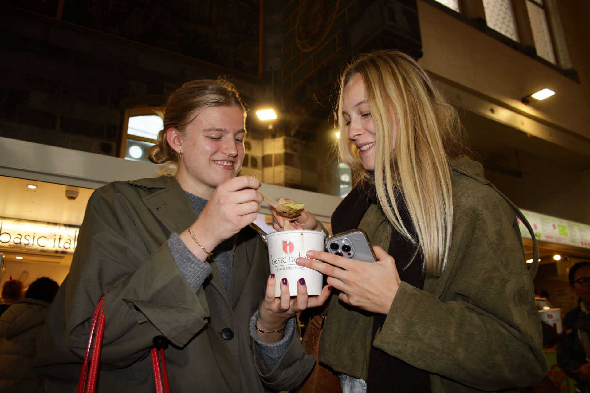 Two girls are eating a pasta from pastabar Basic Italian Ghent