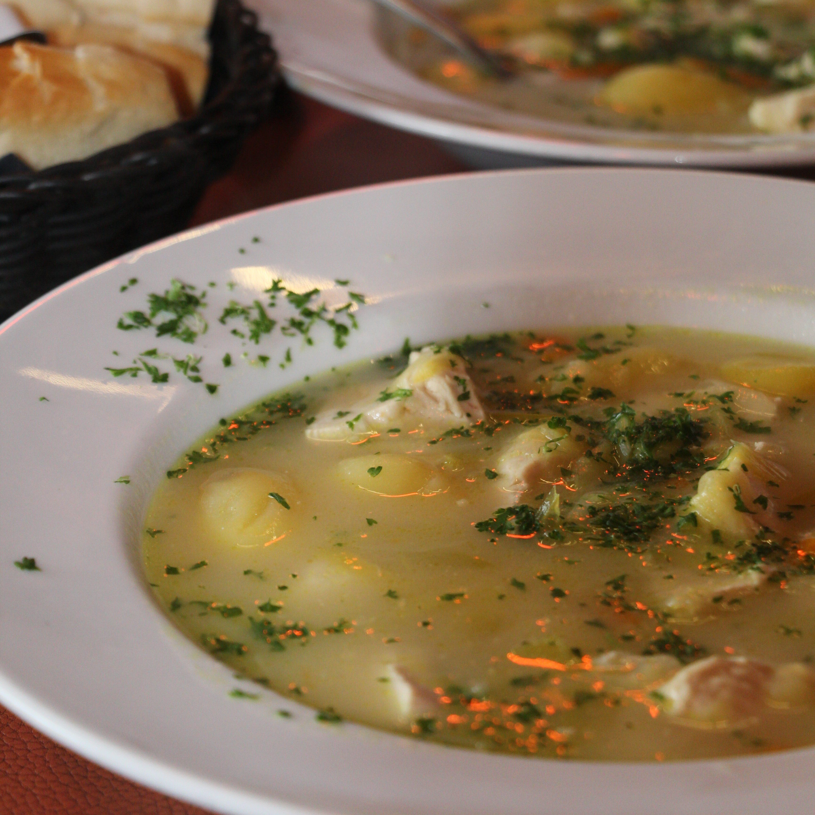 A close-up of a bowl of waterzooi, a traditional Belgian stew, filled with creamy broth, chicken and a mix of vegetables.