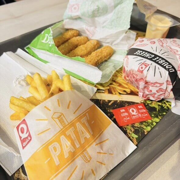 a photo of crispy fries, a cheeseburger, and chicken dipping bites from The Quick, arranged together on a tray