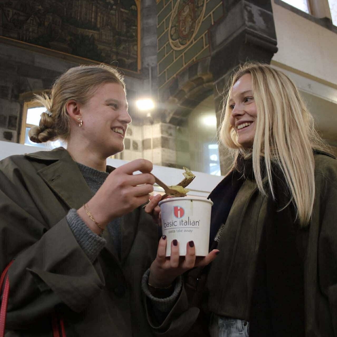 Two ladies are eating a box of pasta pesto in pastabar Basic Italien